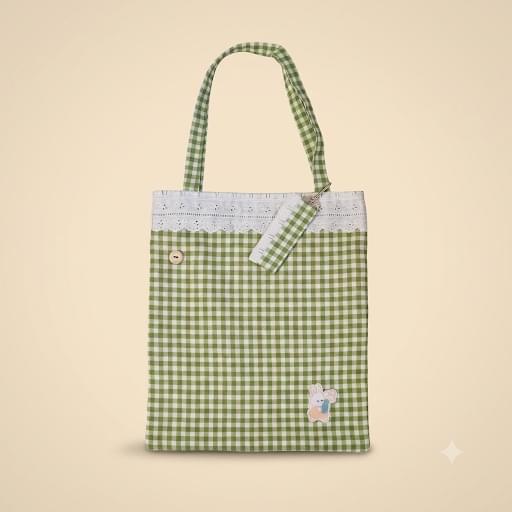 Bolsa tote de vichy verde y blanco con puntilla blanca en el borde superior, botón de madera, aplique de conejito en la esquina inferior y un estuche pequeño a juego colgado del asa.